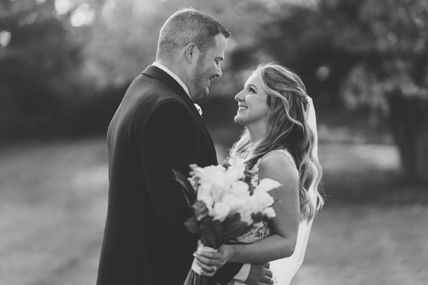 bride and groom looking at each other and smiling during sunset on their Sweeney Barn wedding day