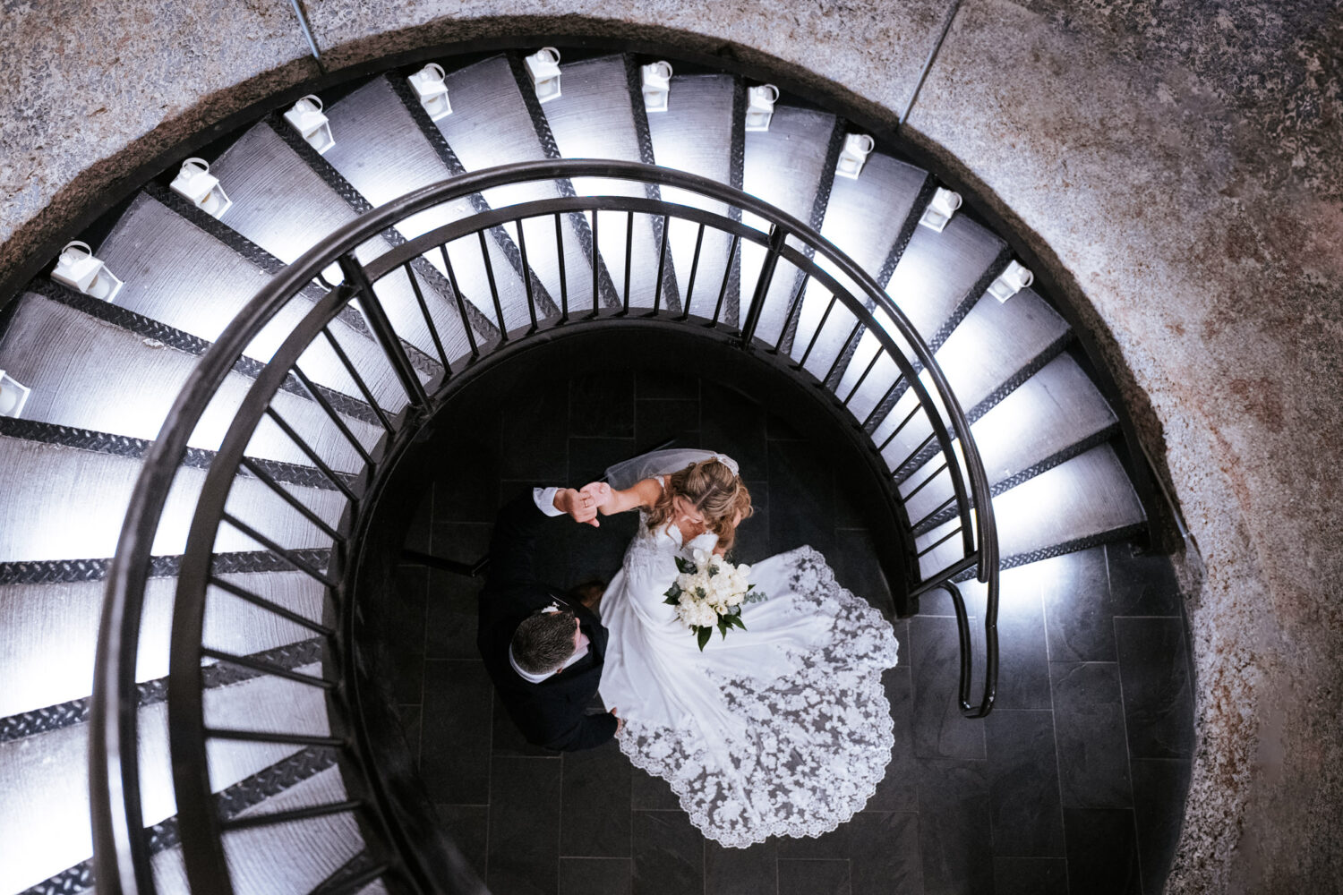 bride doing a spin twirl with her groom on their Sweeney Barn wedding day with a spiral staircase around them