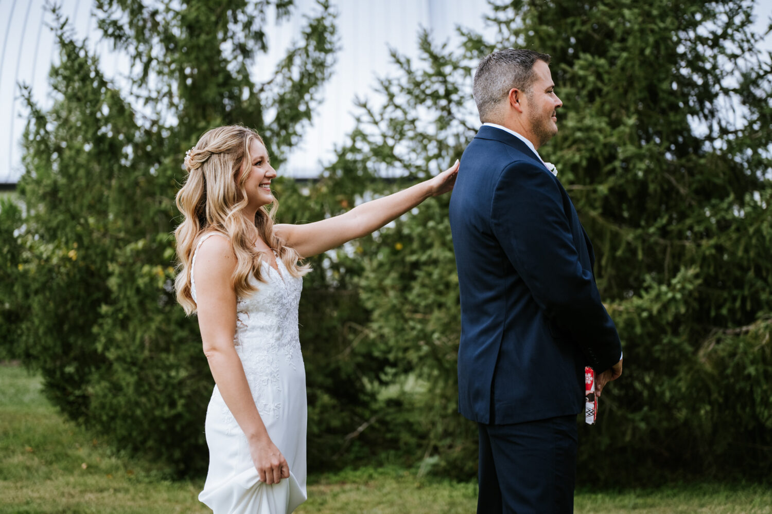 bride tapping groom's shoulder for their first look on their wedding day