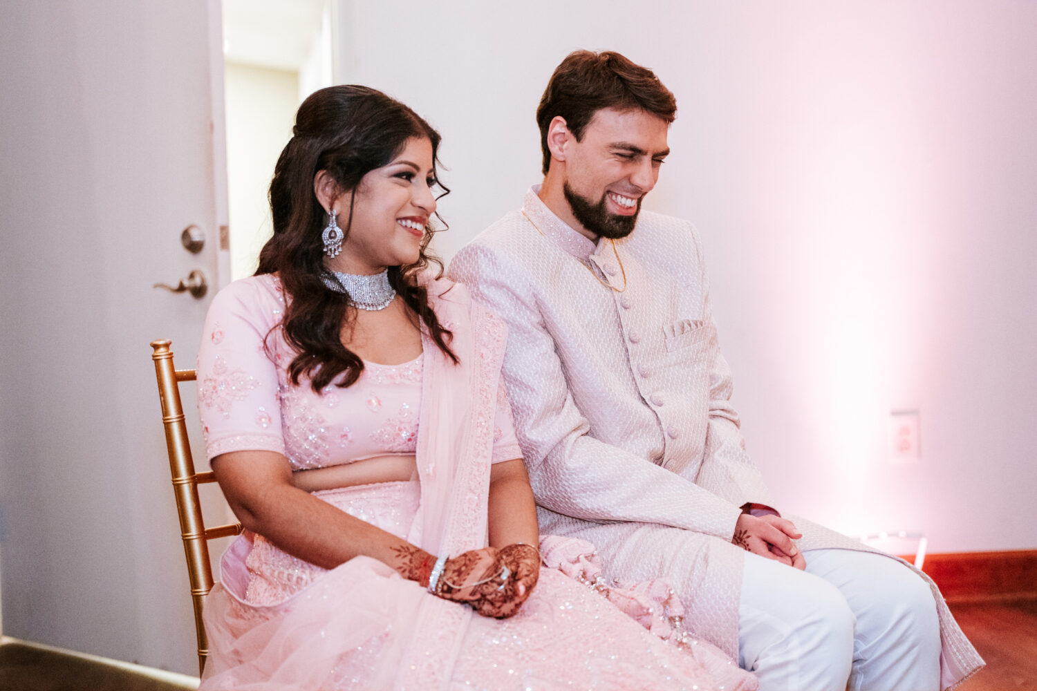 bride and groom smiling while listening to reception speeches