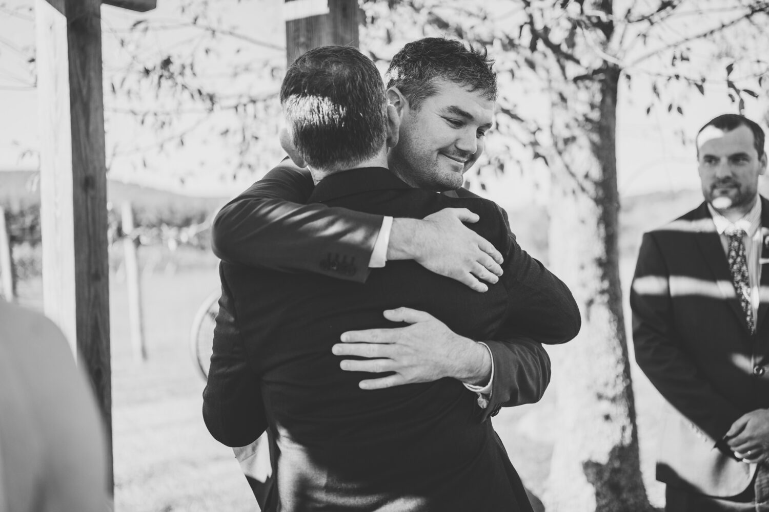 groom hugging his new father-in-law as he walks his daughter to the ceremony space