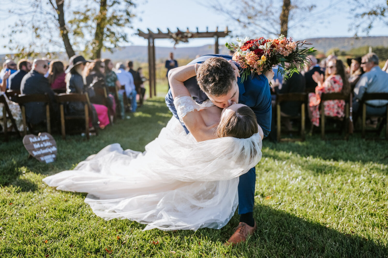 groom giving his bride a dip kiss as they exit their wedding ceremony together