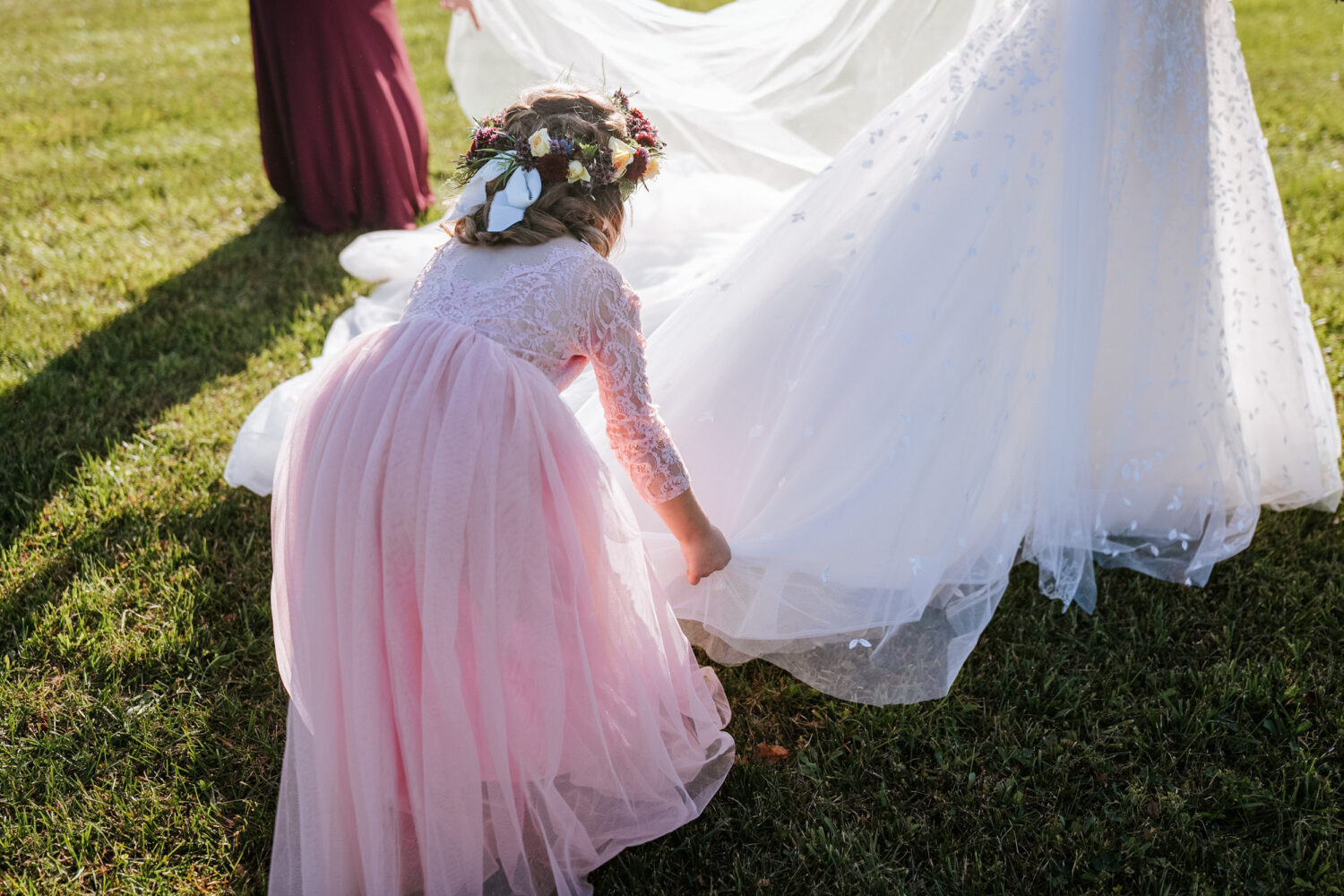 niece of the groom fluffing the bride's wedding dress