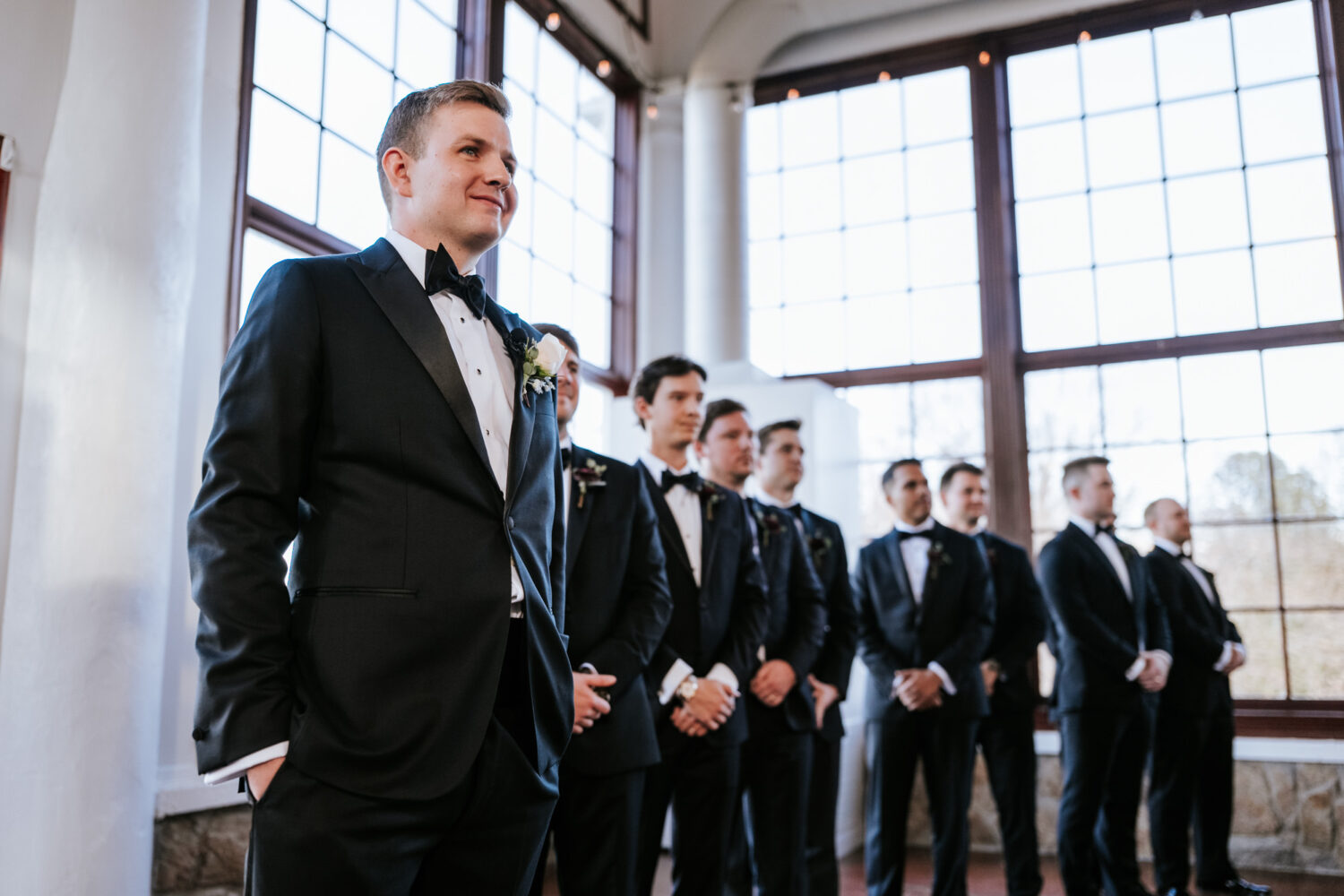 groomsmen smiling while watching bride walk down the aisle