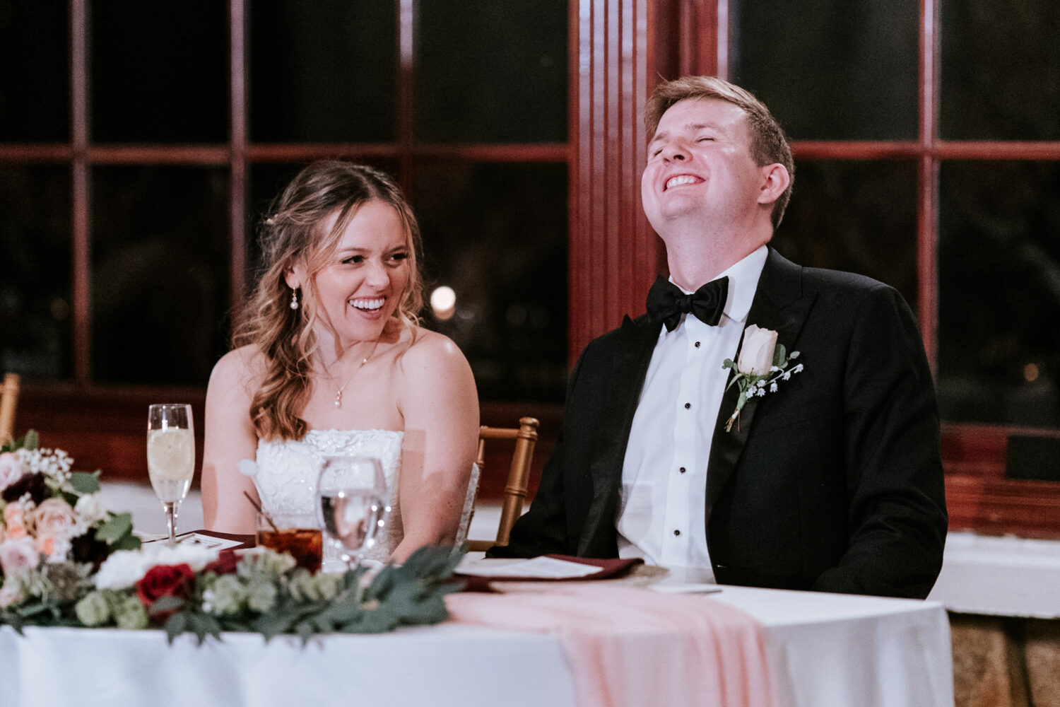 bride and groom laughing while listening to the best man give his speech