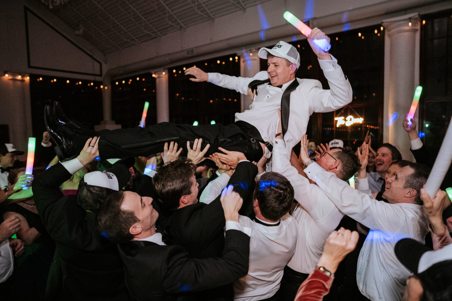 groom being lifted in the air by his wedding guests