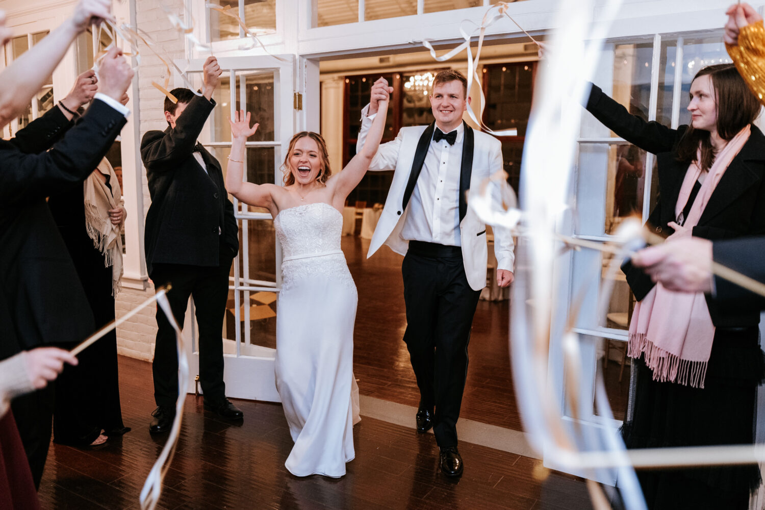 bride and groom walking together while guests use streamers