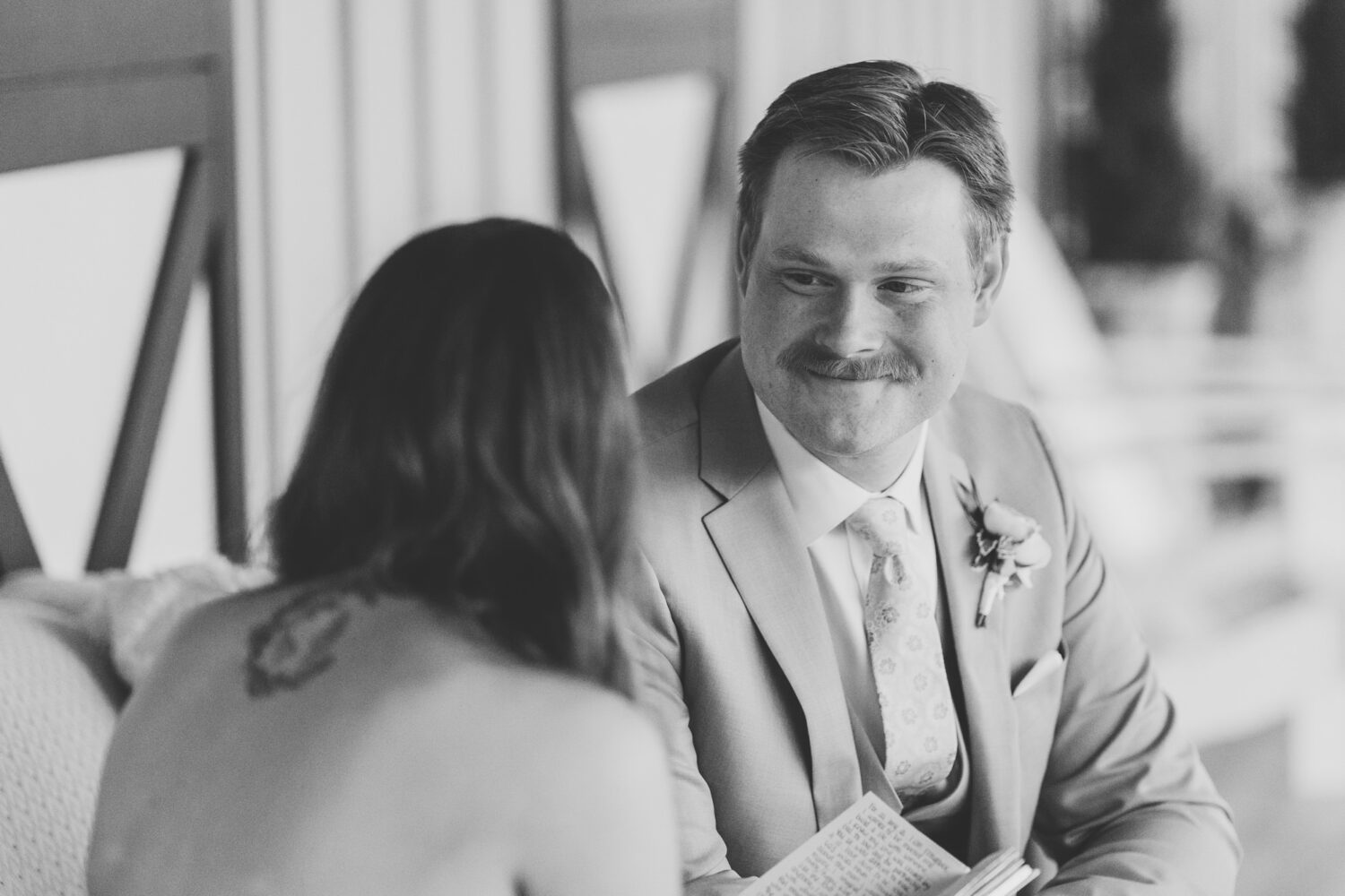 groom smiling while listen to his bride give her wedding vows