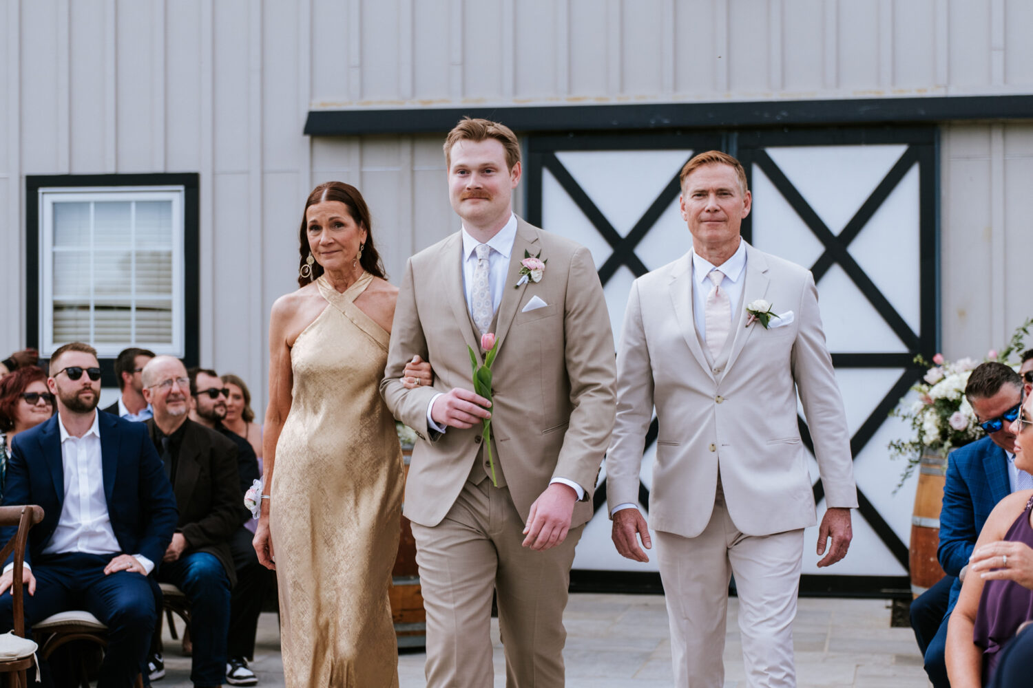 groom walking down the aisle with his parents