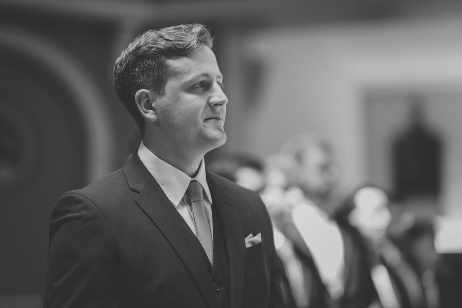 groom smiling while looking at the bride walking down the aisle