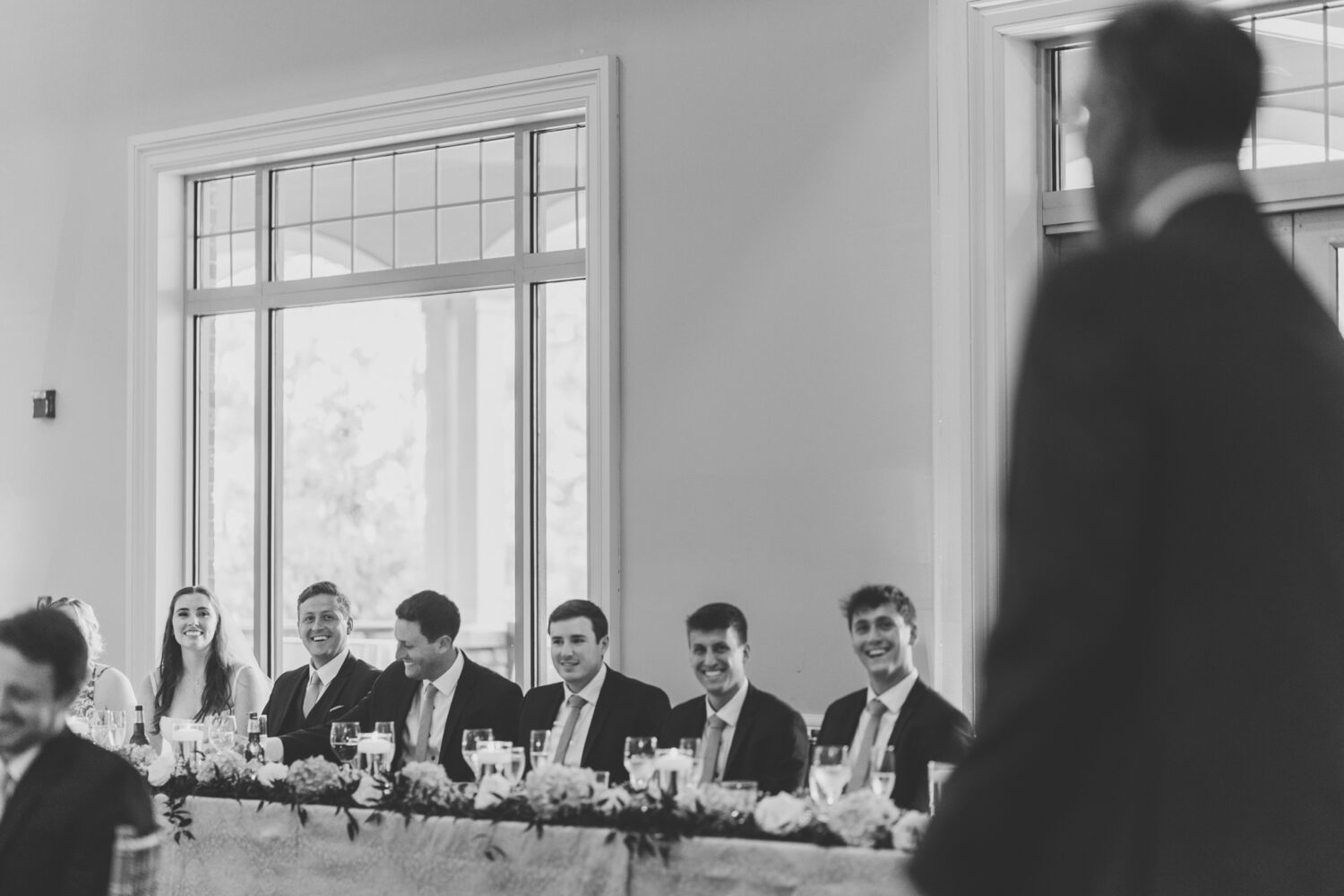 bride and groom smiling while listening to the welcome speech