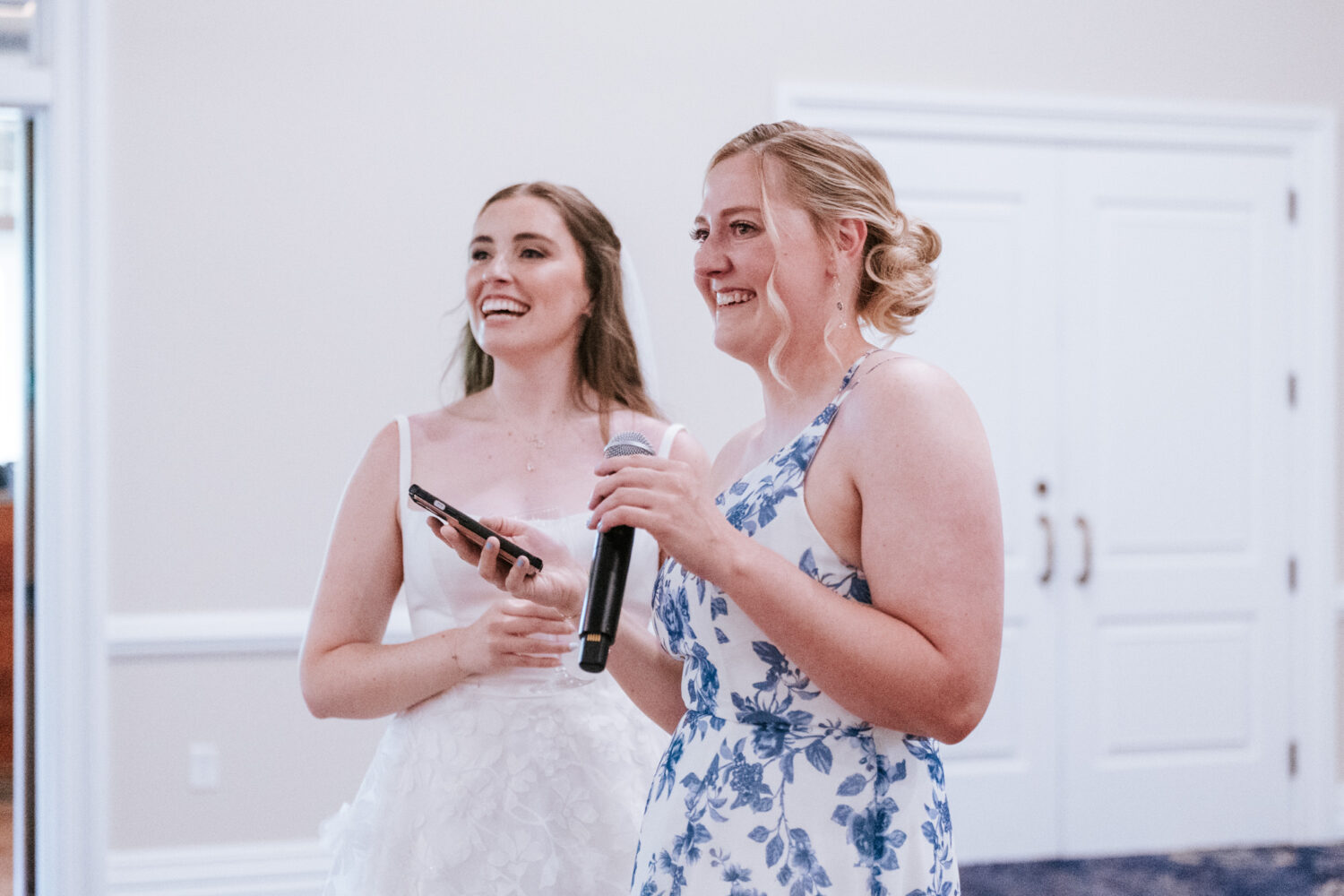 bride and maid of honor laughing together during the maid of honor's reception speech