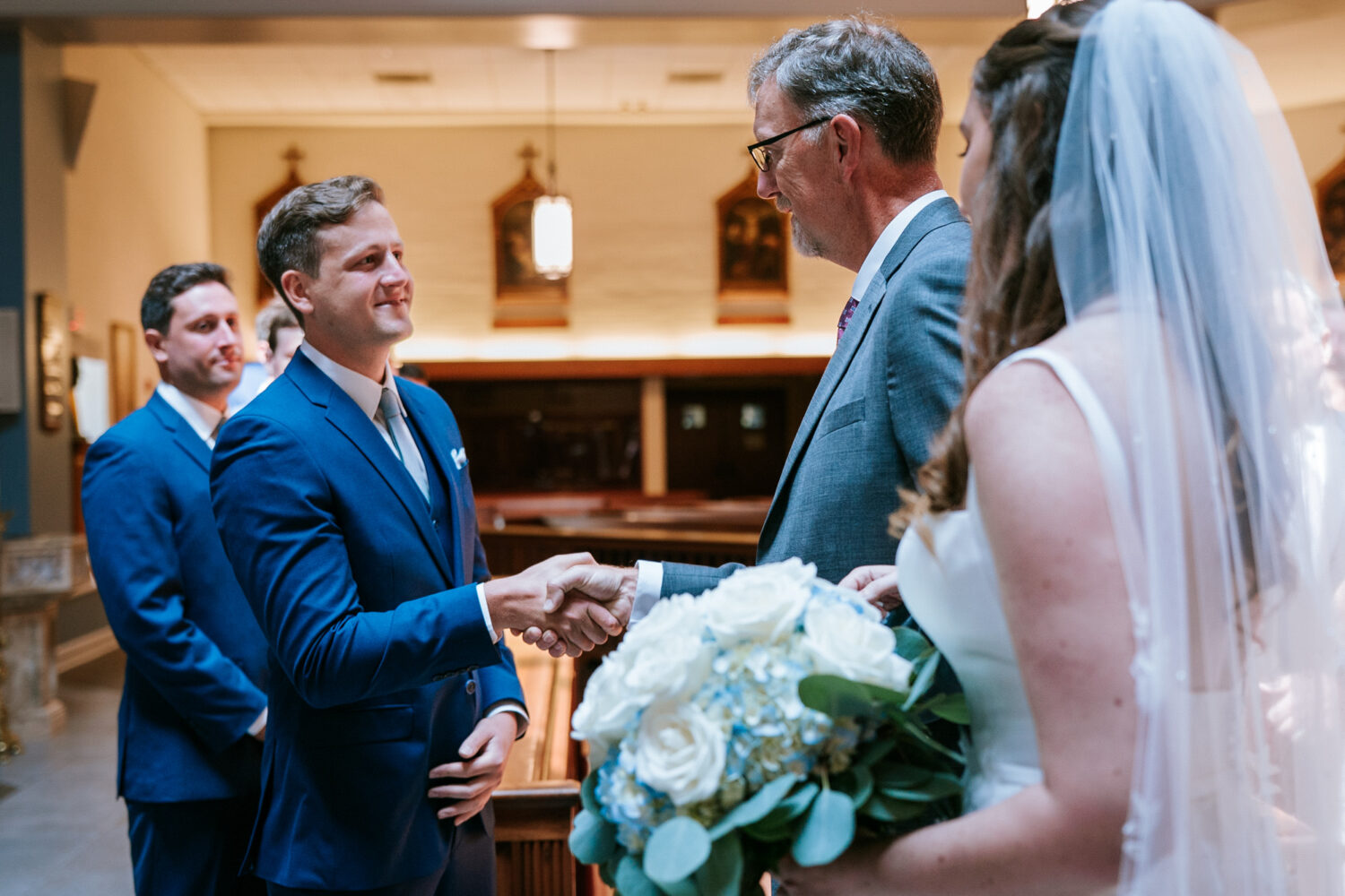 groom shaking the father of the bride's hand during their church wedding ceremony