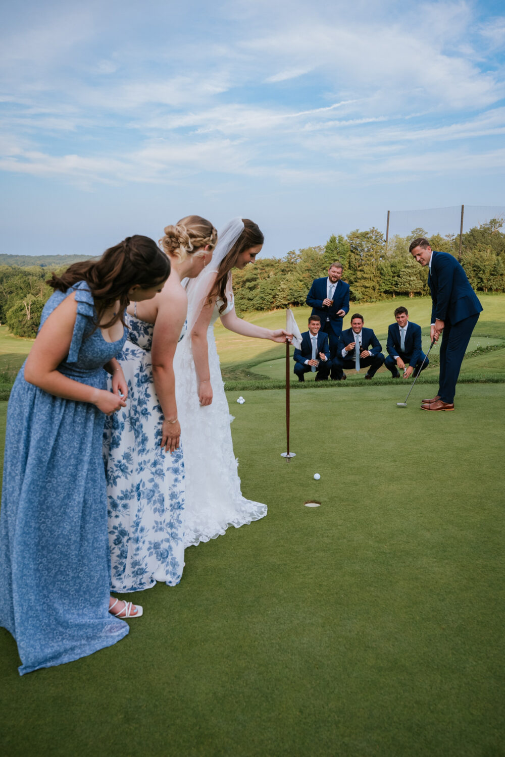bride and groom playing golf with their wedding party watching
