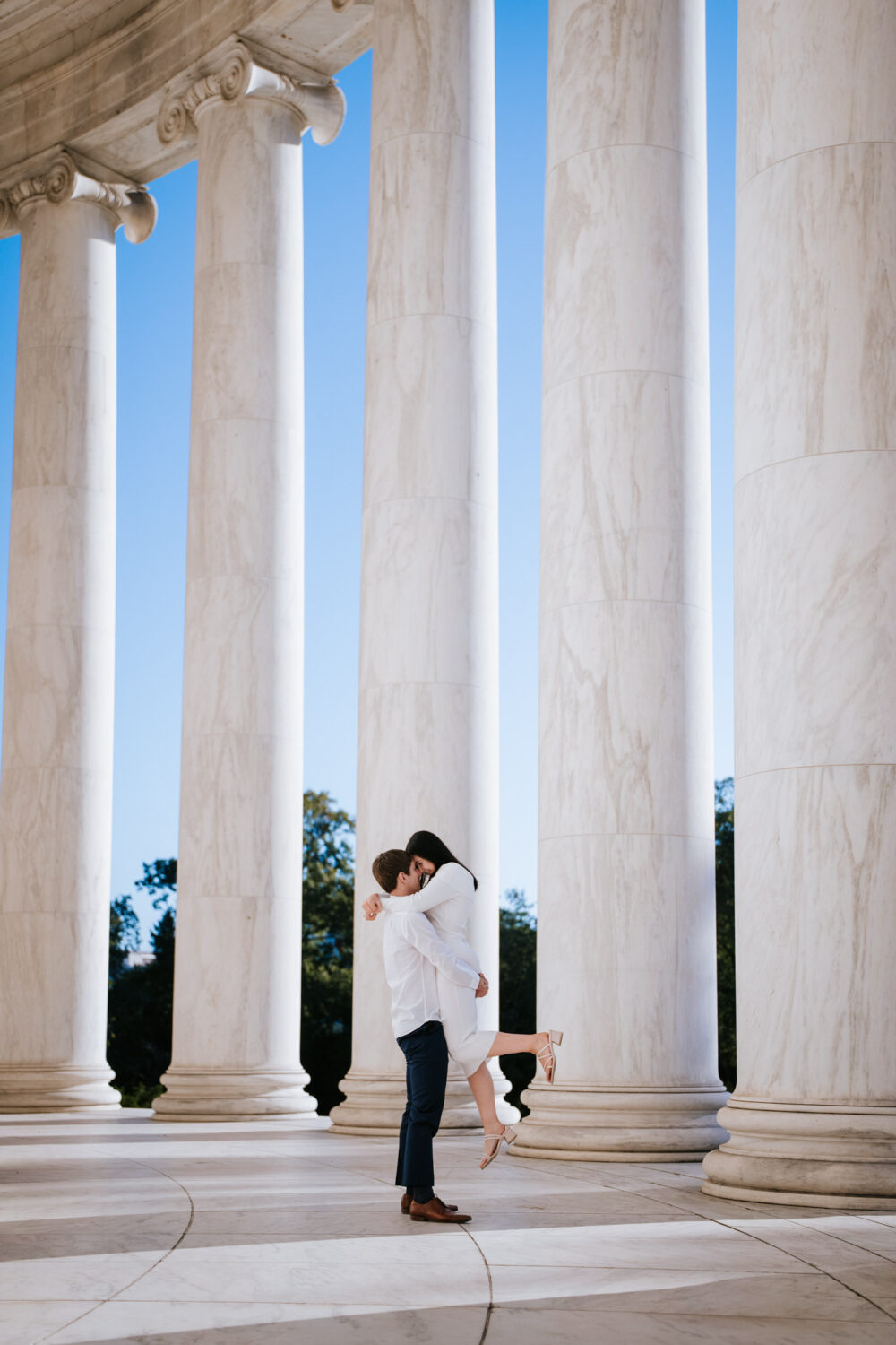 Couple kissing between marble columns for Jefferson Memorial engagement photos in Washington DC