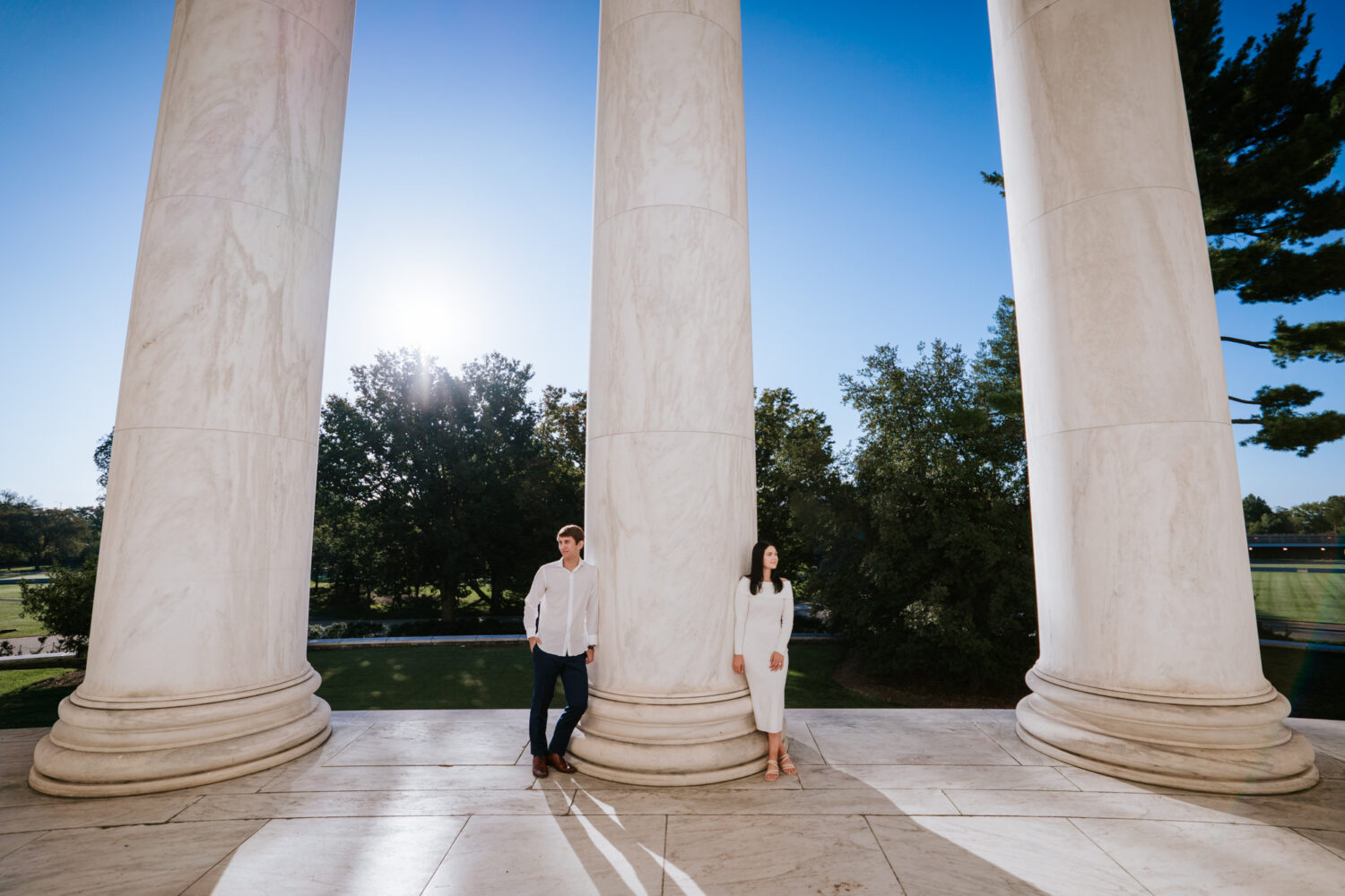 Wide angle engagement photo with couple framed by tall marble columns