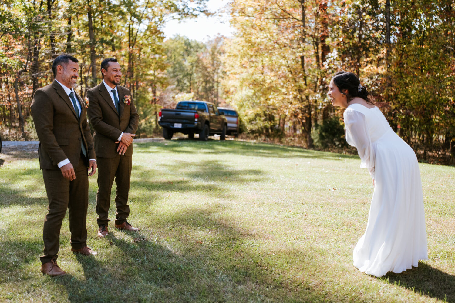Bride laughing during a lighthearted first look with her brothers at fall wedding
