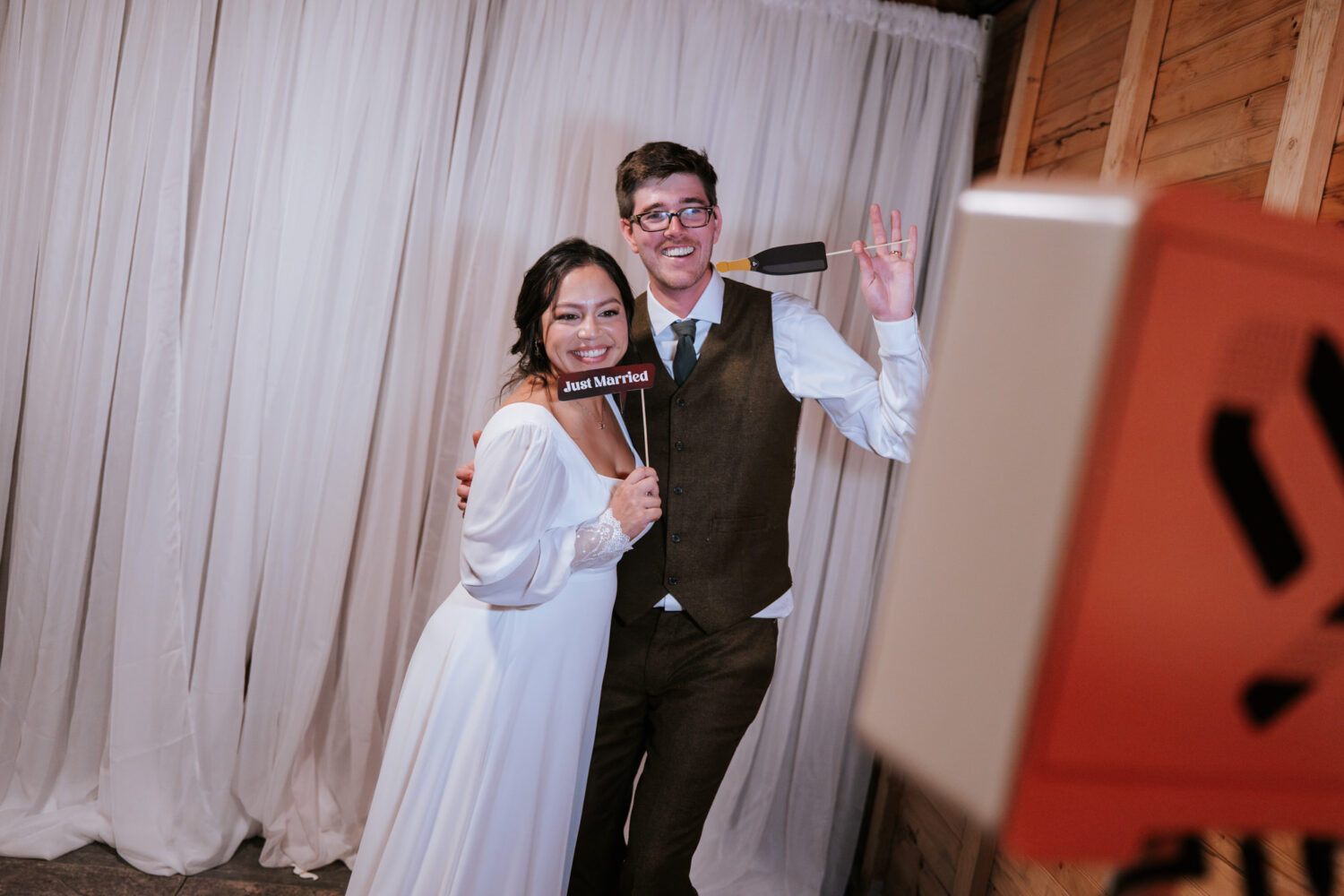Newlyweds pose for a playful photo booth shot with props
