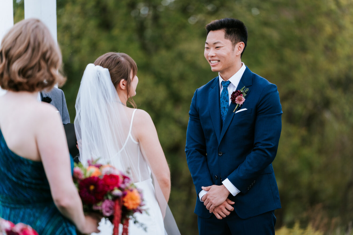 Groom smiling at bride during heartfelt outdoor ceremony
