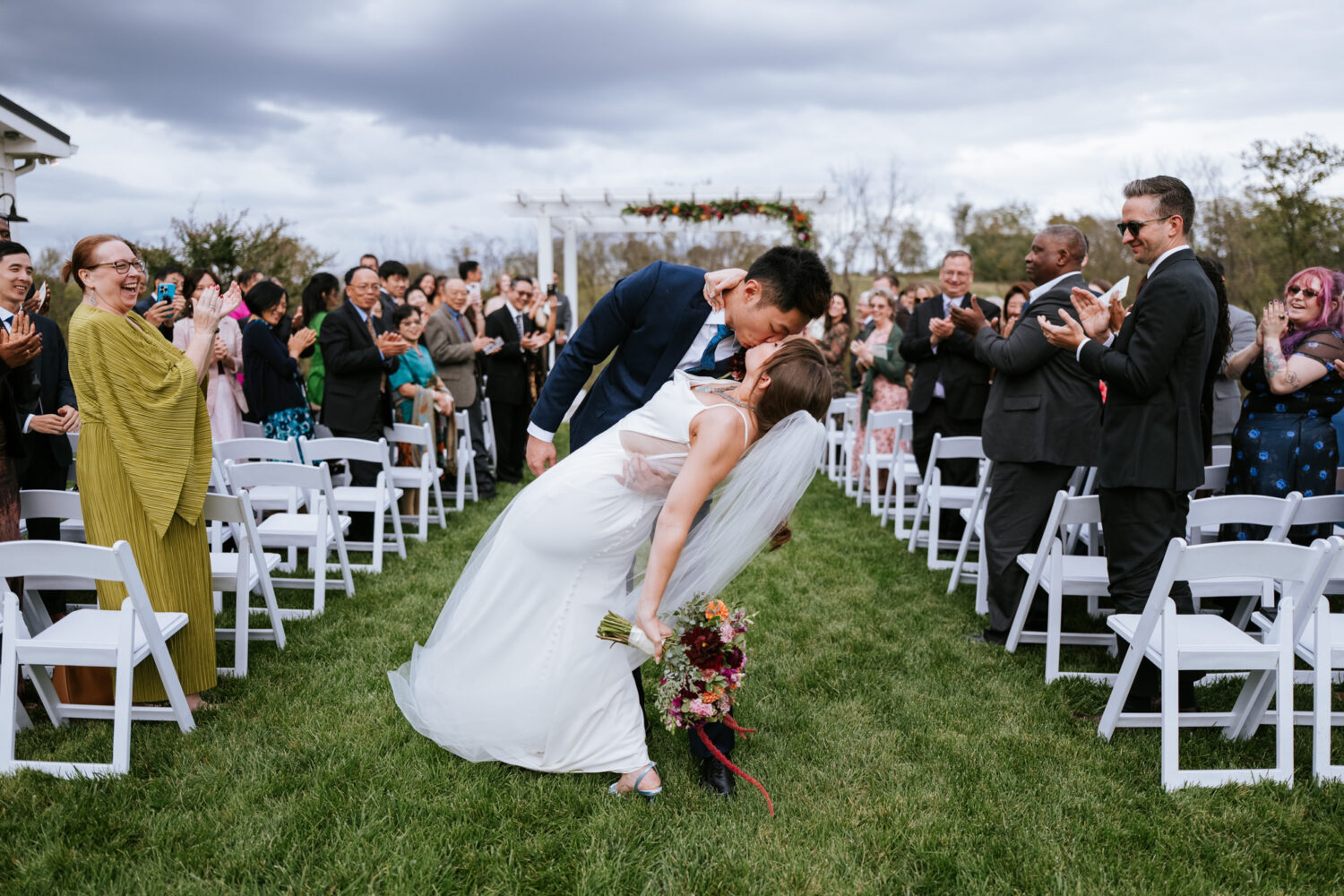 Couple shares a dip kiss at the end of their Willow Brook Barn wedding ceremony
