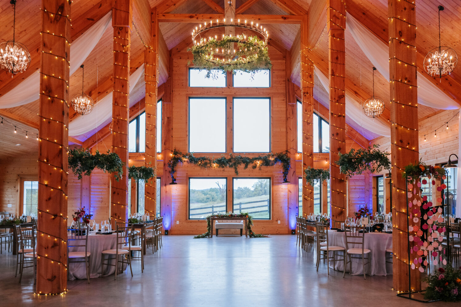 Rustic reception space at Willow Brook Barn with twinkle lights and greenery
