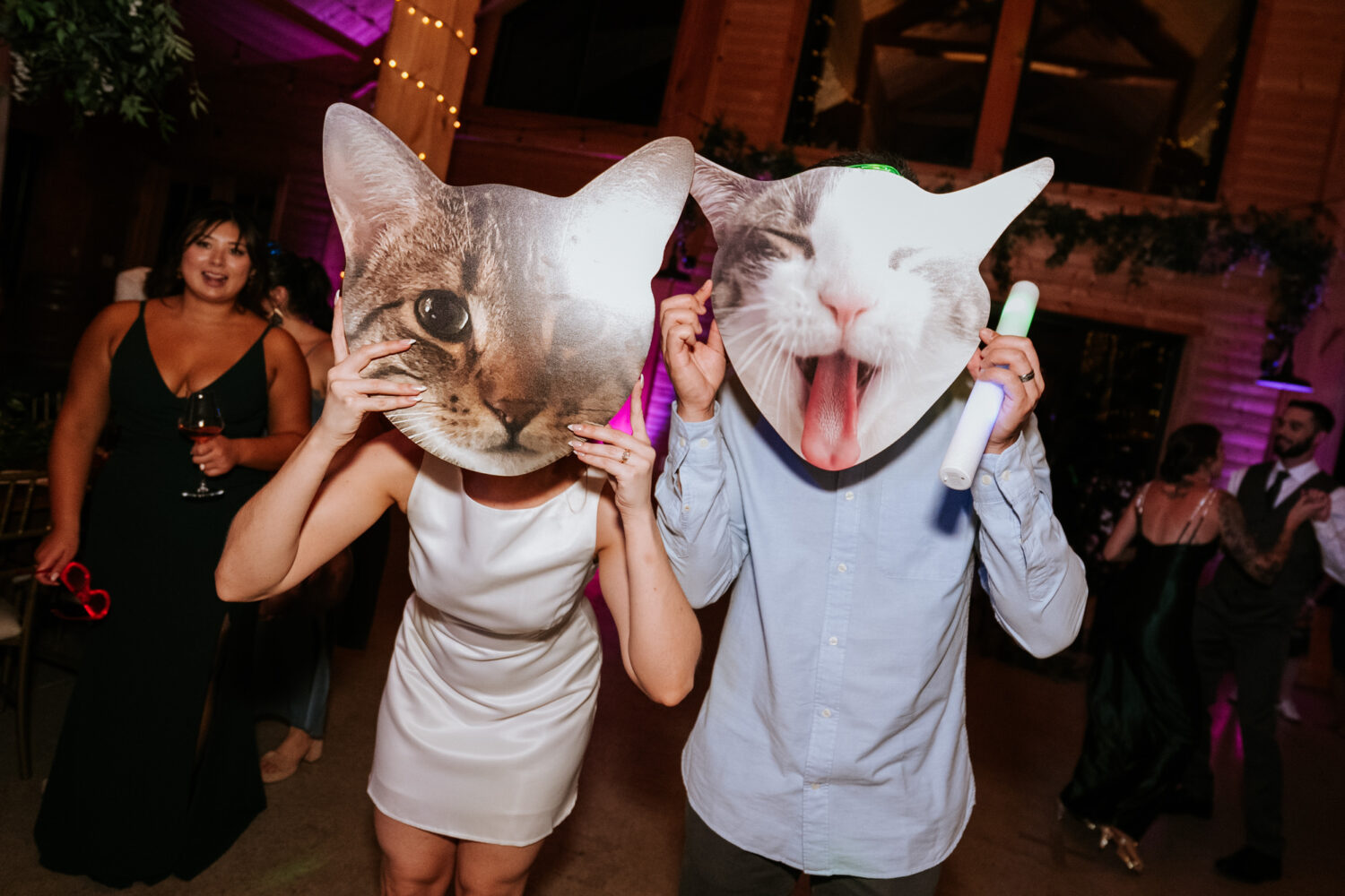 Couple wearing giant cat face masks during a playful moment on the dance floor
