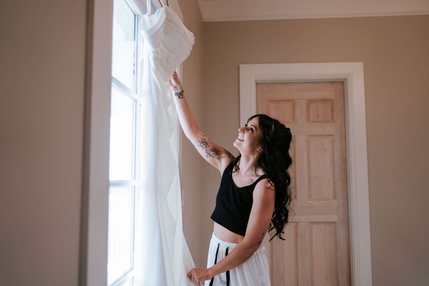 Bride admiring wedding dress by window during getting ready at The View at Bluemont