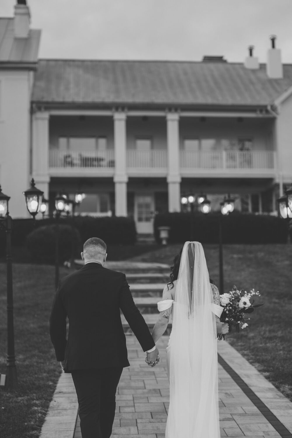 Black and white photo of bride and groom walking toward The View at Bluemont