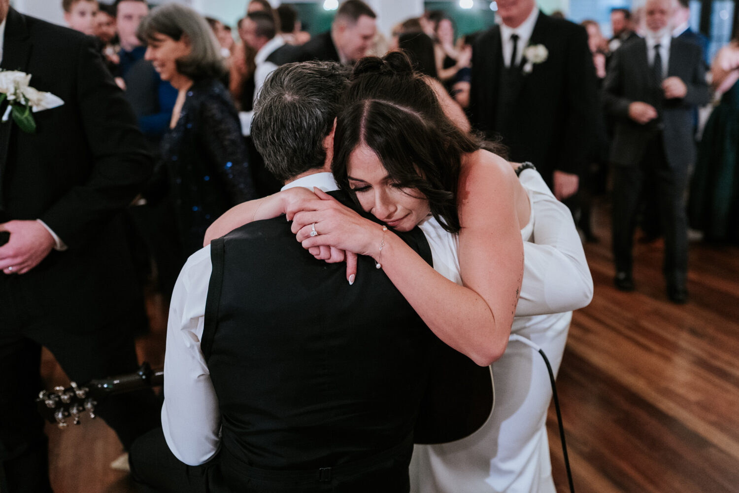 Bride hugging father during emotional live performance at wedding
