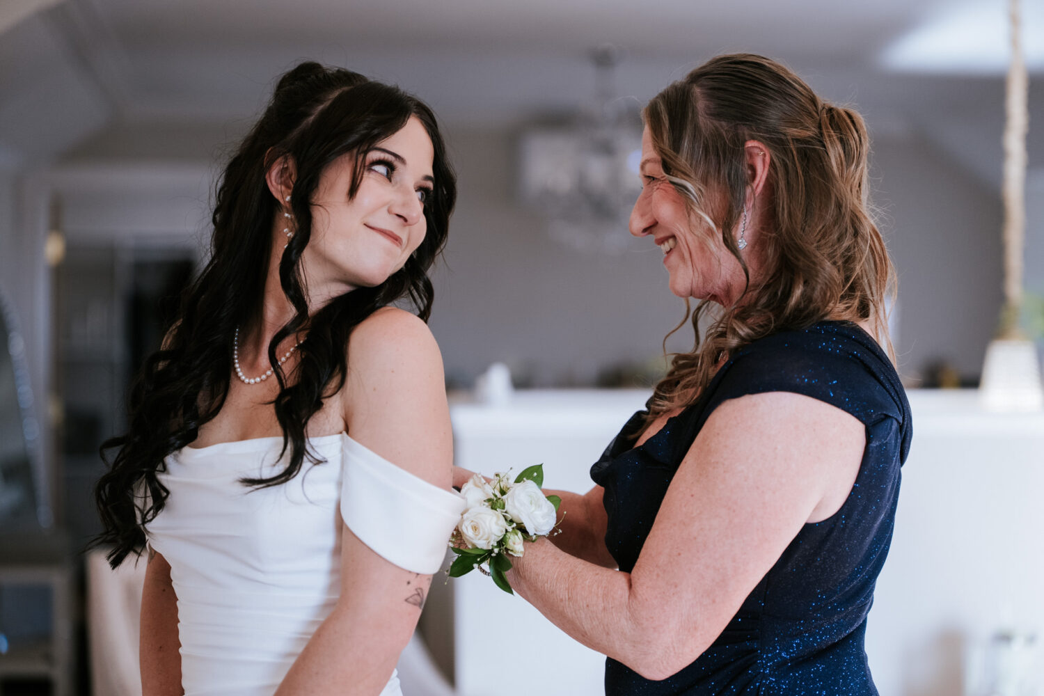 Bride and mother adjusting corsage during getting ready at wedding